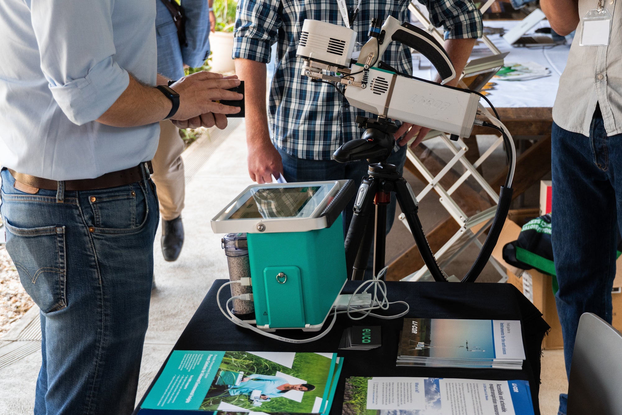 Close-up of the LI‑6800 Portable Photosynthesis System on display at the EUCA stand during the SAAB Conference, with attendees discussing its features and brochures laid out on the table.